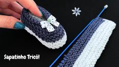 a crocheted slipper with a bow is being held by someone's hand