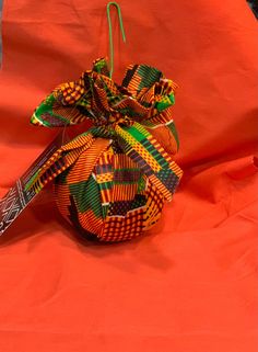 an ornament with a bow on it sitting on top of a red cloth