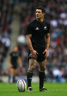 a rugby player standing next to a soccer ball on a field with spectators in the background