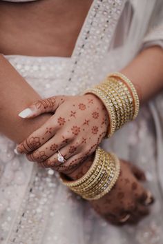 a close up of a person with henna on their hands and bracelets around their wrists