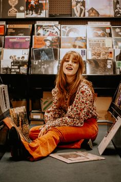 a woman sitting on the floor with her legs crossed in front of bookshelves