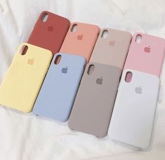 six iphone cases are lined up on a white sheet with an apple logo in the middle