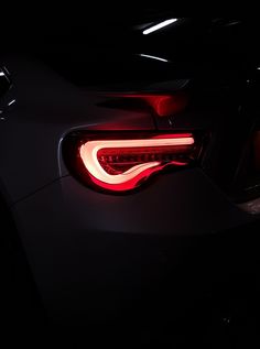 the tail light of a black sports car in the dark with its brake lights on