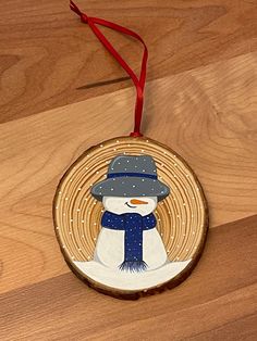 a wooden ornament with a snowman wearing a hat and scarf on it