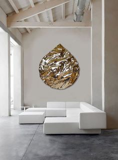 a living room with white couches and a large gold leaf wall hanging on the wall