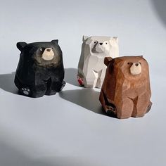 three different colored bears sitting next to each other on a white surface with one bear facing the camera