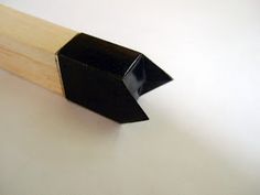 a black piece of wood sticking out of the side of a wooden stick on a white surface