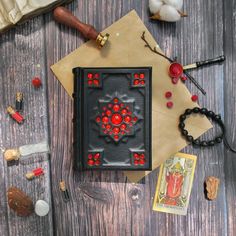 a book with red flowers on it sitting next to some other items and beads around it