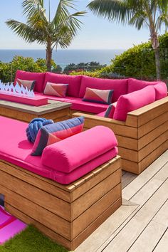 an outdoor seating area with pink cushions and palm trees in the background, overlooking the ocean