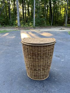 a wicker basket sitting in the middle of a parking lot with trees in the background