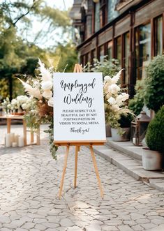 a sign that is on top of a wooden easel with flowers in front of it