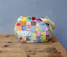 a multicolored patchwork purse sitting on top of a wooden table