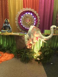 an elephant statue sitting on top of a table next to a green cloth covered wall