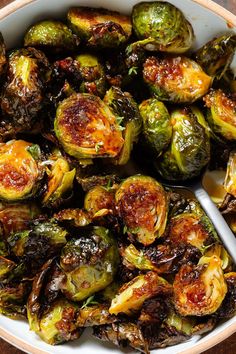 brussel sprouts in a white bowl with a spoon on the side