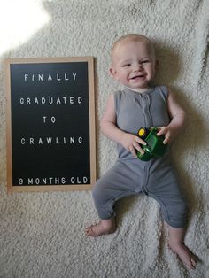 a baby laying on the floor next to a sign that says finally graduate to crawling 8 months old