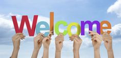 several hands holding up the word welcome in front of a blue sky with white clouds