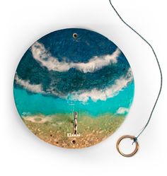 a round plate with a painting on it and a keychain hanging from the side