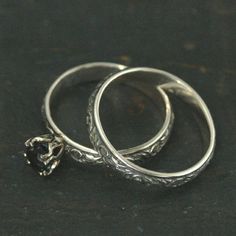 two silver wedding rings sitting next to each other