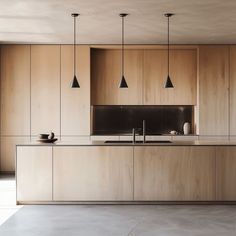 an empty kitchen with wooden cabinets and black lights hanging from the ceiling, in front of a large window