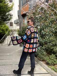 a woman is walking down the sidewalk wearing a crocheted jacket