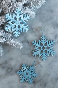 two snowflakes are hanging from a tree