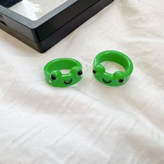 two green bracelets sitting on top of a white bed next to a black box