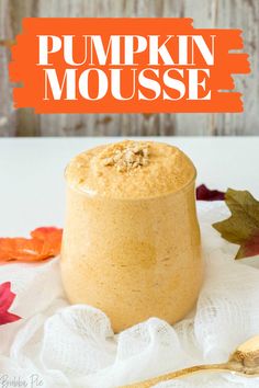 pumpkin mousse in a small glass jar on a white tablecloth with leaves around it