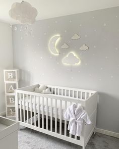 a baby's room with a white crib and clouds painted on the wall