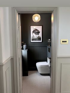 a white toilet sitting in a bathroom next to a black and white wall with a painting on it