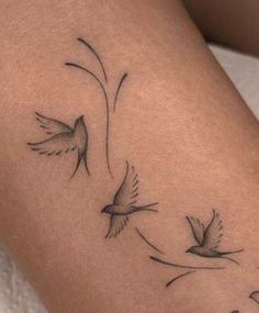 a woman's arm with three birds flying in the air and one bird on it