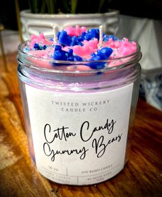 a glass jar filled with pink and blue candies on top of a wooden table