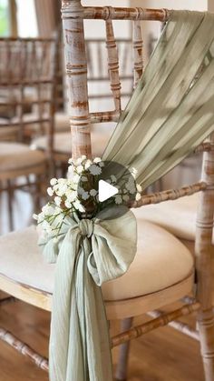 a chair with a bow tied around it and flowers on the back of it's seat