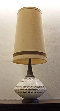 a lamp sitting on top of a wooden table next to a white and brown vase