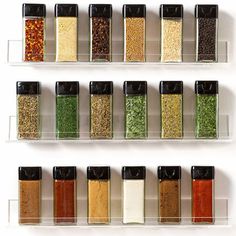 spices and seasonings are lined up in glass containers on the wall above each other