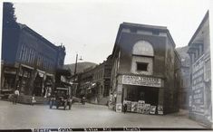 an old black and white photo of people walking in front of a theater on a street corner