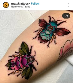 a close up of a person's arm with tattoos on it and two flowers