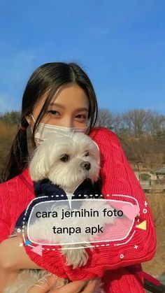 a woman holding a small white dog in her arms