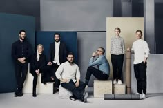 a group of men standing and sitting next to each other in front of blue walls