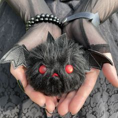 a person holding a stuffed animal with red eyes and bats on it's hands