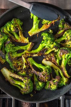 broccoli florets are being cooked in a skillet on the stove