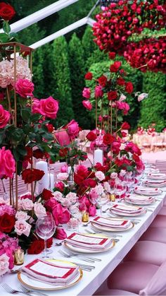 a long table with pink and red flowers on it is set up for a wedding reception