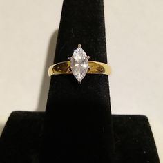 an engagement ring with a pear shaped diamond on it's side, sitting on a black velvet stand