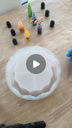 someone is making an art project with plastic cups and paint bottles on a table top