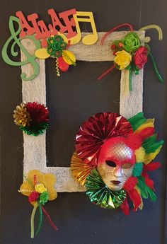 a decorated photo frame hanging on the wall with paper flowers and decorations in front of it