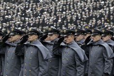 a group of uniformed men standing next to each other in front of a large crowd