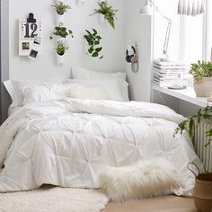 a bedroom with white bedding and plants on the wall