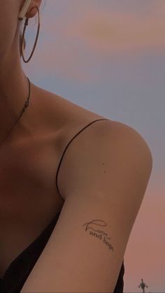 a woman with a small tattoo on her arm and the sky in the back ground