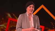 a woman standing in front of a red and black background with an orange house on it