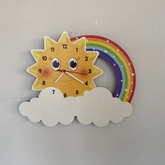 a clock with a sun face and rainbow in the background, on a white wall