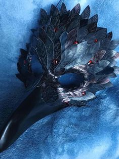 a mask with feathers on it laying on a blue blanket